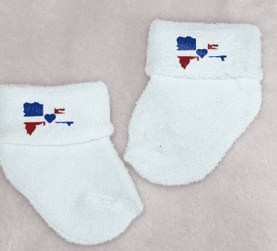 Baby socks with the Dominican Republic flag shaped like the Island of the Dominican Republic. There is a blue heart in the center where the crest would normally be.