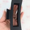 Black XL hair claw clip with hollow center held in womans palm to show size of hair claw measurements.