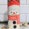 Snow man with santa hat on a stainless steel 20 oz tumbler. Background is a red and black tartan pattern with snowflakes.