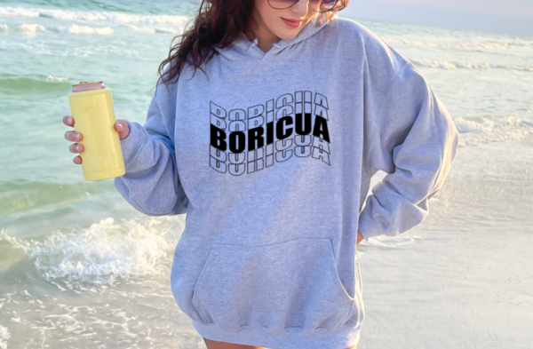 Woman wearing a gray hoodie with the word Boricua echoed written in a wavy font in black