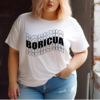 Plus sized woman wearing a white t-shirt with the word Boricua echoed and written in wavy font in the color black.
