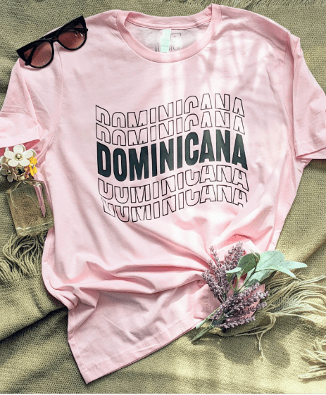 Pink T-shirt with the word "Dominicana" written in a wavy font across the chest in the color black.