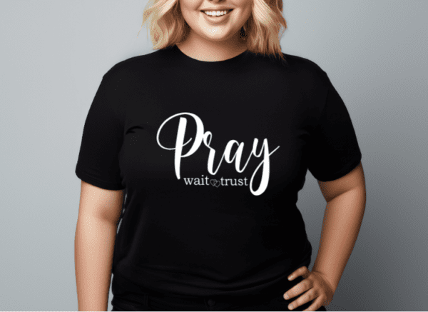 Woman wearing a black t-shirt with the phrase "Pray Wait Trust" written across the chest in white.