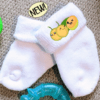 White baby socks with the image of 3 quenepa buddies on the side.