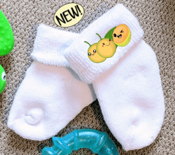White baby socks with the image of 3 quenepa buddies on the side.