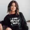 woman wearing a black crewneck with the phrase "You never fail until you stop trying" written in warped text.