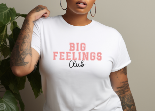 woman wearing a white t-shirt with the phrase "Big Feelings Club" written in pink and black.