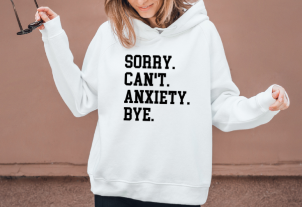 woman wearing a white hoodie with the phrase "Sorry. Can't. Anxiety. Bye" in a collegiant font.