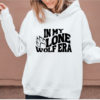 woman wearing a white hoodie with the phrase "In my lone wolf era" written in a retro wavy font and a wolf paw print next to the word "lone"