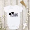 White one-piece baby bodysuit with the phrase "Cool Like Mi Madrina" with the silhouette of sunglasses diagonally on the side.