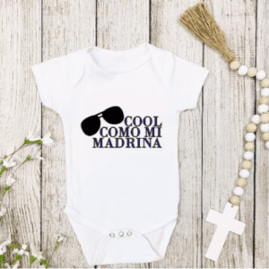 White one-piece baby bodysuit with the phrase "Cool Like Mi Madrina" with the silhouette of sunglasses diagonally on the side.