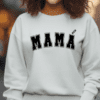 Woman wearing a white crewneck sweatshirt with the word "MAMA" written on the front with an accent over the second A like Latinos would say it.