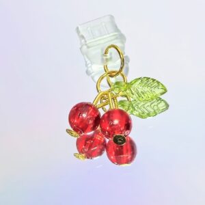 summer phone charm. two small resin cherries with one small green leaf held together with gold wires and connected to a clear silicone usb-c dust plug